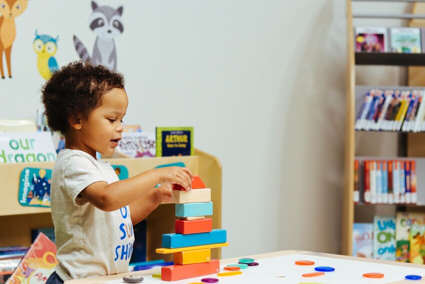 A small child uses building blocks at an activity table at West Olympia Timberland Library