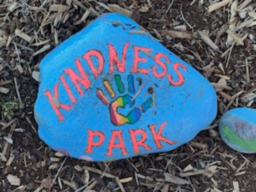 A stone with a rainbow handprint that says Kindness Park