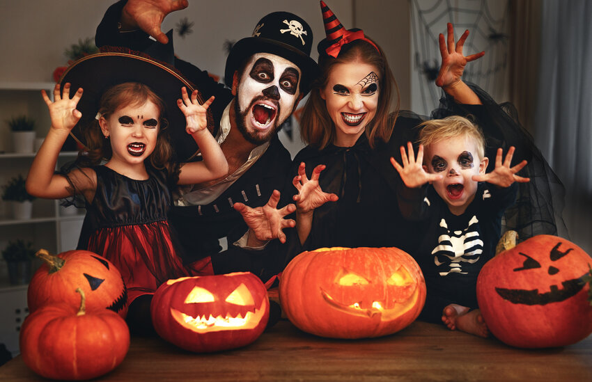 A family getting spooky in their Halloween costumes with their Jack-O-Lanterns