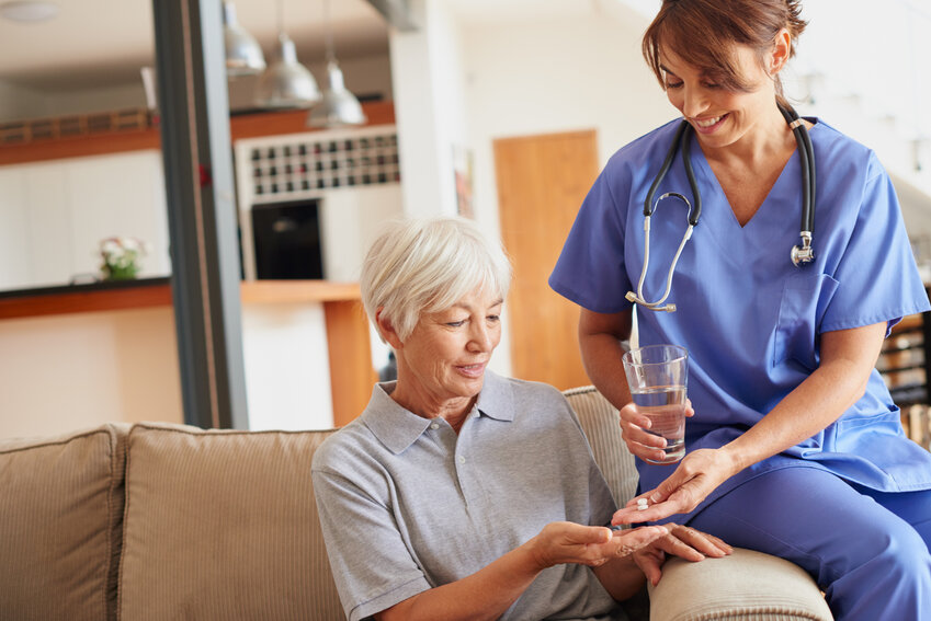 A woman nurse or doctor giving an elderly patient medication.
