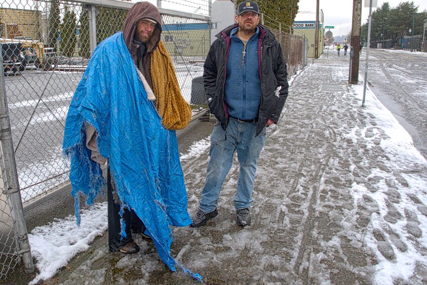 Two unidentified homeless men weathered the Valentine's Day nighttime snowstorm.  The man on the left commented that he had been homeless for 12 years. When asked about the tarp and towel he said, "It's all I could find to stay warm and dry with all this snow."