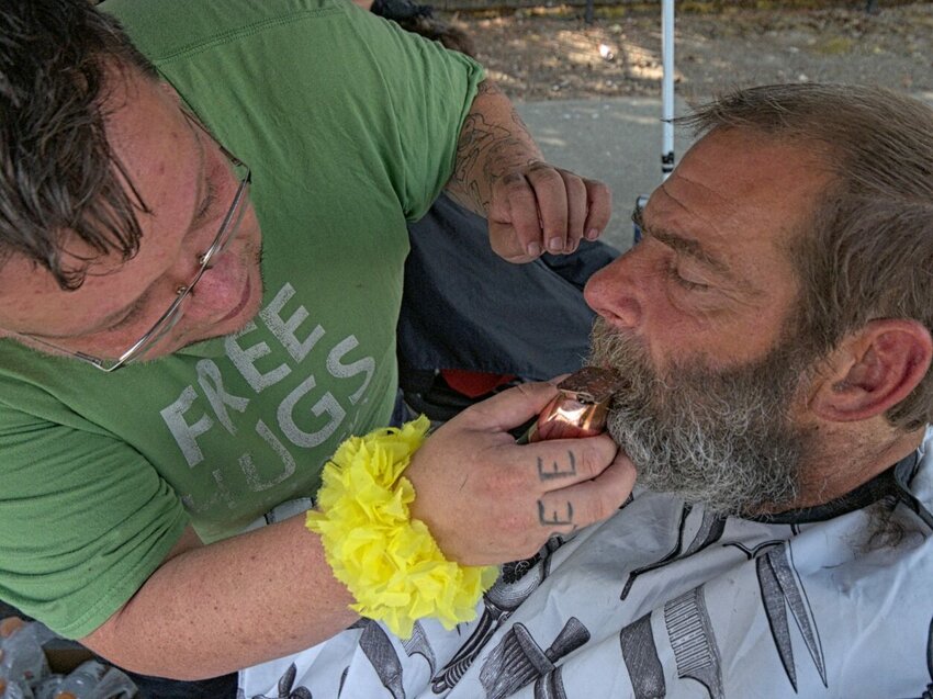 Stuart Wilson, left, a student at Olympia Barber School, trims a local man’s moustache and beard. 