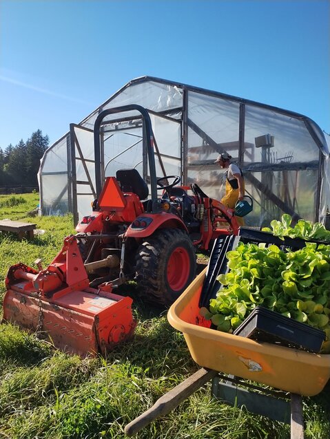 James Wirth prepping fields for planting at Calliope Farm. Tractor in foreground with high tunnel in background.