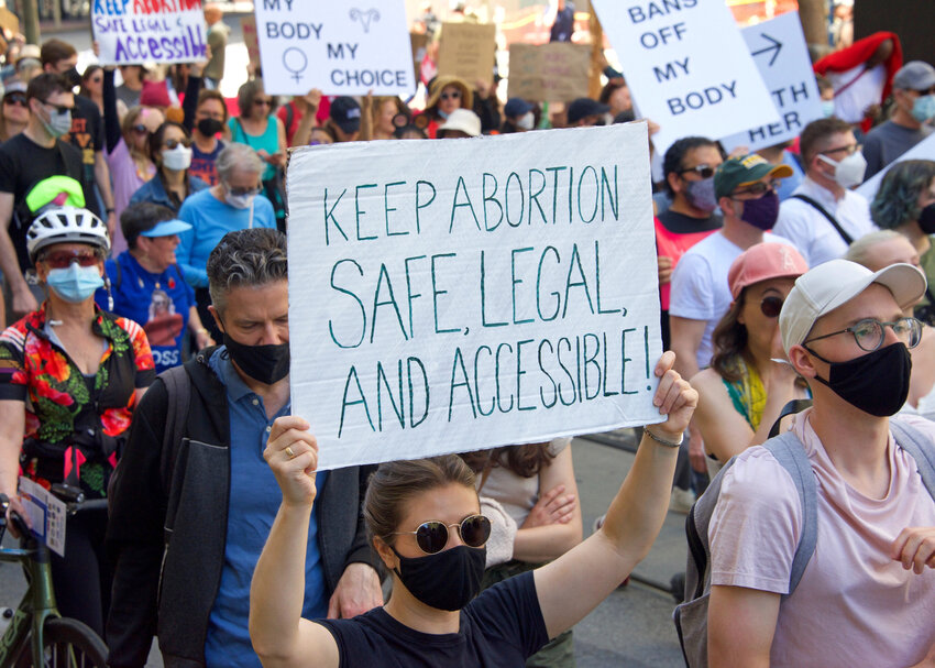 Woman holding a sign that says "keep abortion safe, legal, and accessible!"