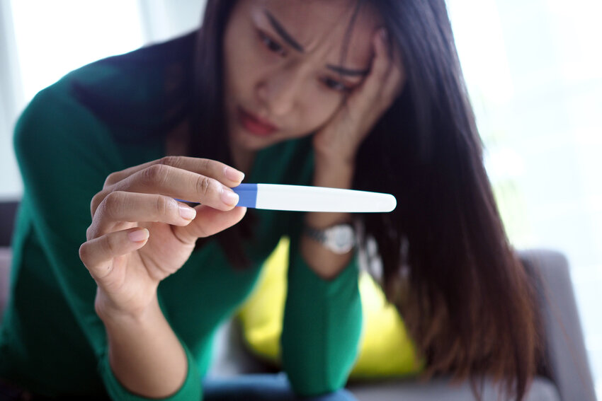 An asian woman stressed and worried about pregnancy results.