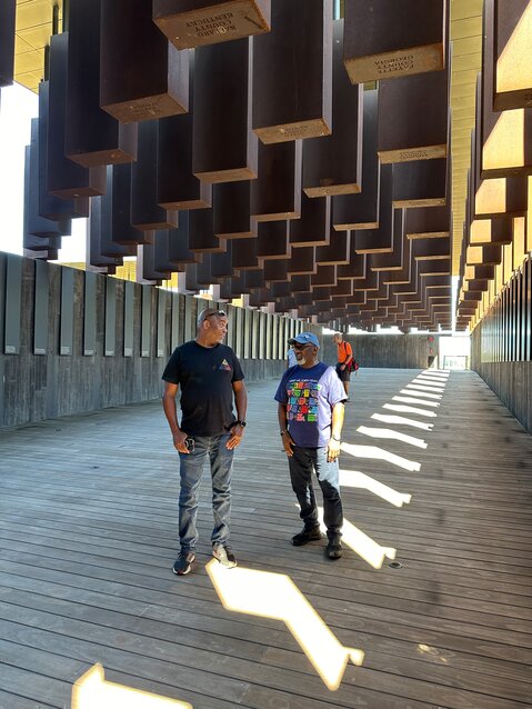 Pierre, left, and Jarvis standing inside the simple but explosive display of mass tragedy that lynching was (each column has the names of individual lynched in each county) at an Equal Justice Initiative site.