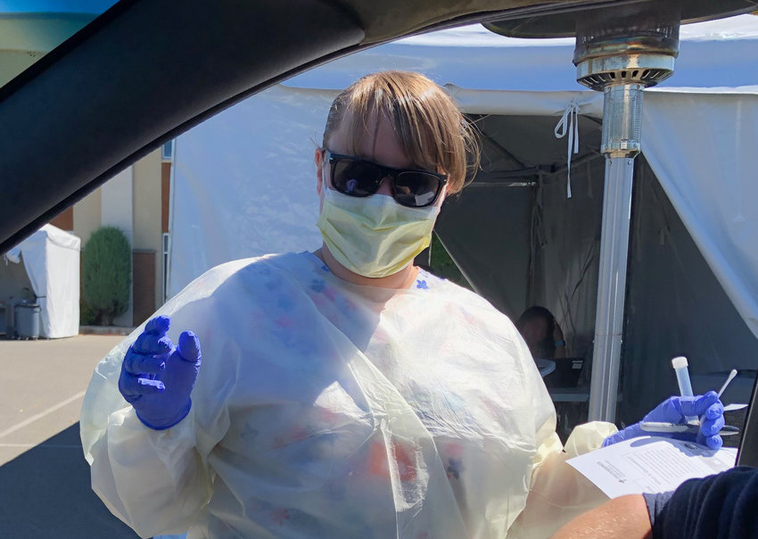 Medical assistant Amanda Fennell seemed to be smiling as she prepared to administer a COVID-19 test in near 80 degree weather on Monday, July 20, 2020.