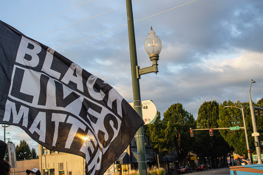 A protestor holds a Black Lives Matter flag at Heritage Park in Olympia.