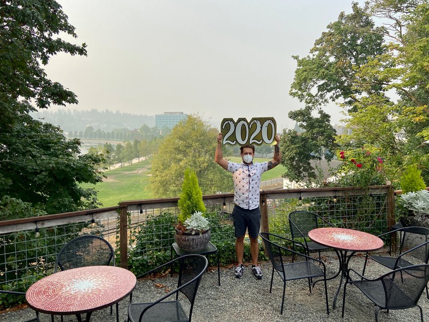 Contrasting today's smoky atmosphere against the same view just over two weeks ago, Swing Wine Bar bartender John Swetz holds a sign previously used to optimistically welcome the New Year.