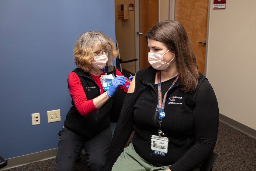 Elizabeth Vadnais administers the COVID-19 vaccine to Ashlynn Strode on Dec. 18. The pair, nurses for Providence in Southwest Washington, were among the first to receive the COVID-19 vaccine in Southwest Washington.