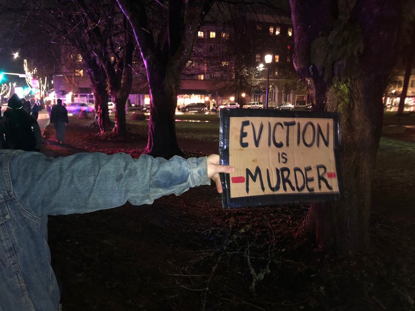 &quot;Eviction is murder&quot; reads the sign of a protestor standing across the street from the Olympia Red Lion Inn on Sun., Jan 31, 2021.