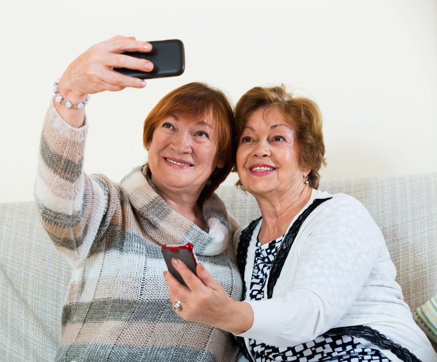 Modern happy mature women using mobile phone for image together