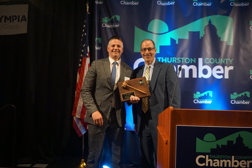 Joseph Lanham, left, accepts a plaque commemorating his year as board chair of the Thurston County Chamber of Commerce from David Schaffert, CEO of the organization.
