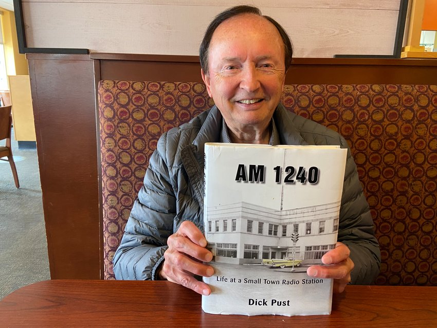 Dick Pust holds a copy of his new memoir, AM 1240: Life at a Small Town Radio Station.