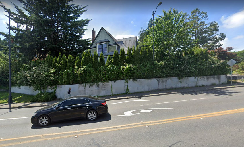 For reference only, this image shows the retaining wall on Olympic Way before it was painted with the Climate Justice Mural-- and before the new family painted the house above it purple over purple.