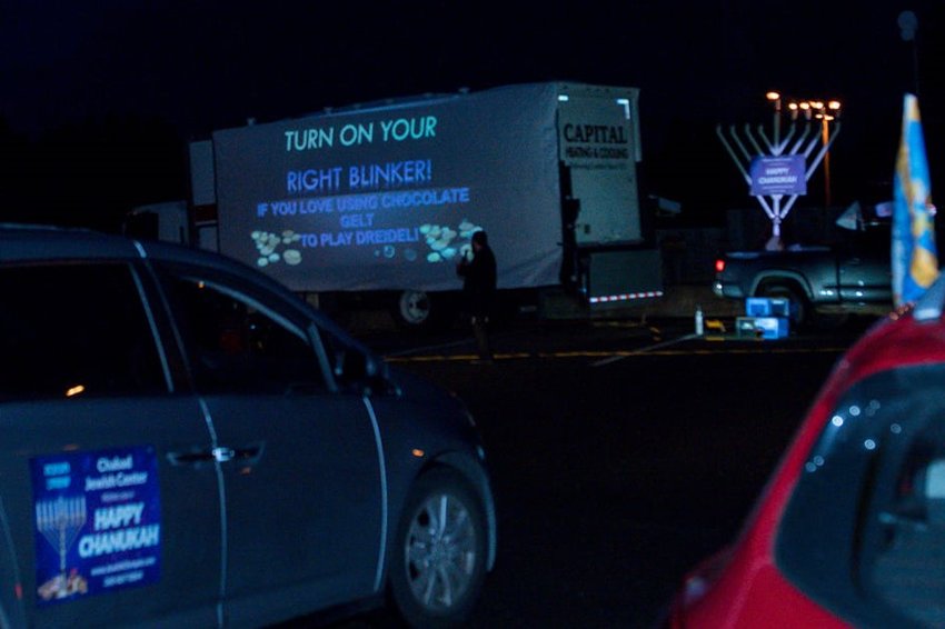 In a scene from the 2020 Chabad Chanukah event, Rabbi Yosef Schtroks leads a game-show type activity in front of the assembled cars.