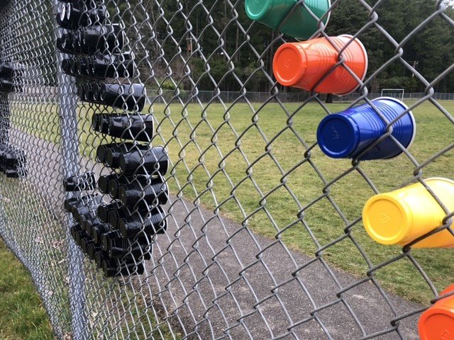 Plastic cups pushed through the fence form the letters in Boston Harbor Elementary School's display.