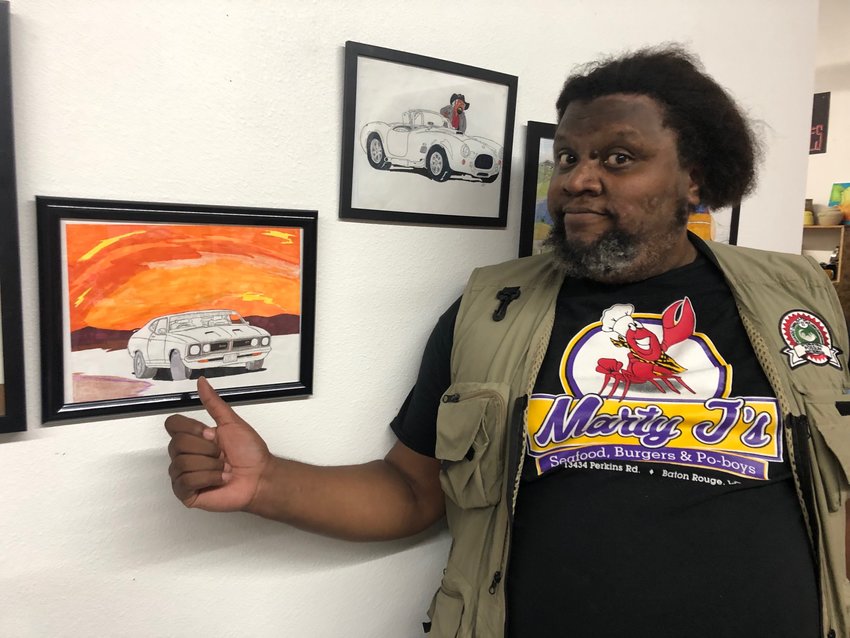 Logan &quot;Snoopy&quot; Chrysler stands next to some of his art on exhibit until September 4, 2022 at Gallery Boom in Olympia.