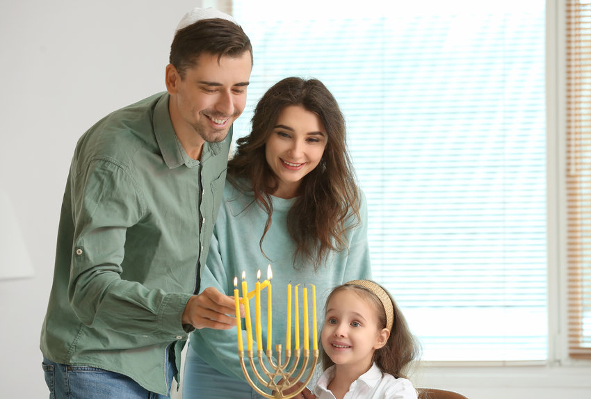A Jewish family lighting candles for Hannukah at home. This image does not depict it, but many Jewish people are Jews of&nbsp;color with different appearances and backgrounds.