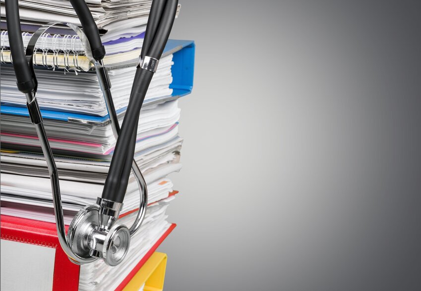 Stethoscope on a large pile of paperwork.