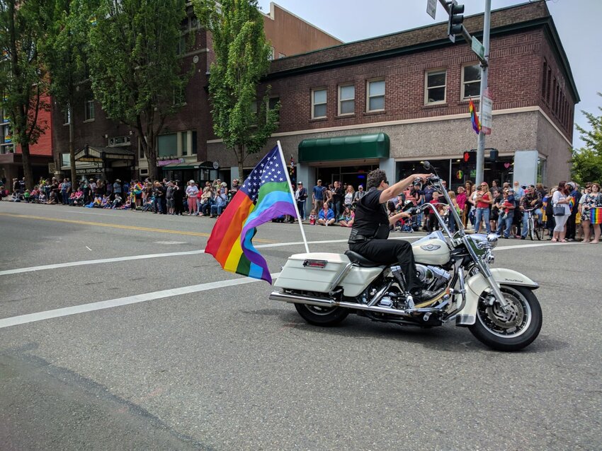 A motorcyclist drives down the street with a rainbow American flag during the Pride Parade in Olympia, 2017