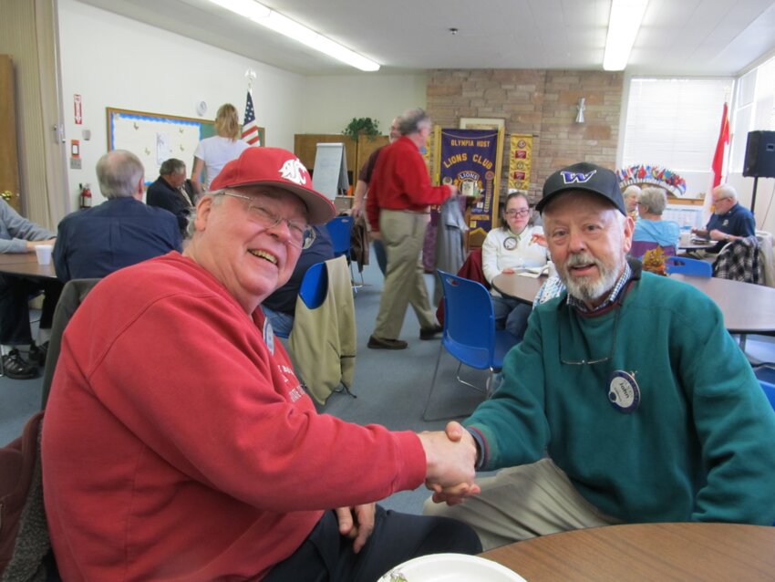 James Reddick (left in red), shaking hands with John Calhoun at a Lions Club meeting in Olympia.