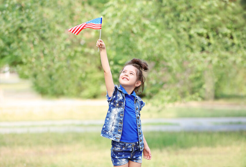 Small girl with the American flag in park.