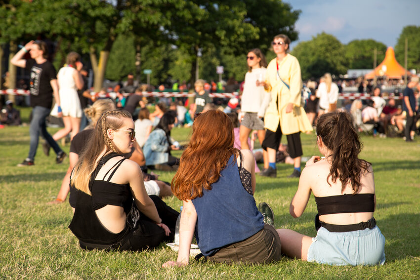 People sitting on grass and enjoying sunshine at an outdoor summer event