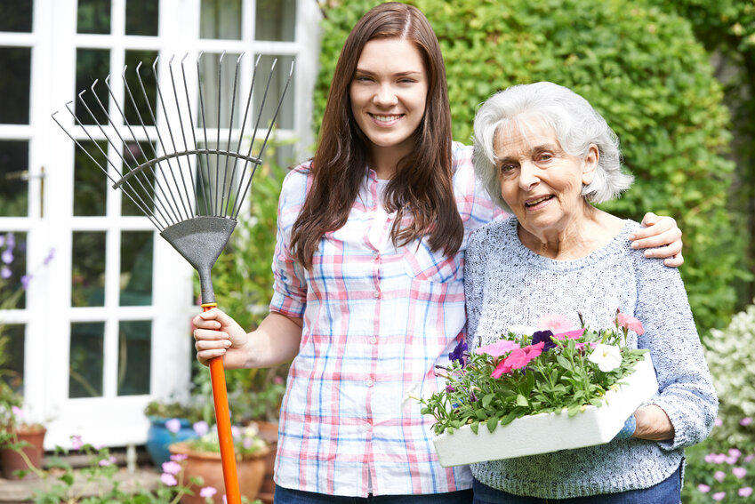 Younger woman helping an elderly woman around the house and garden.