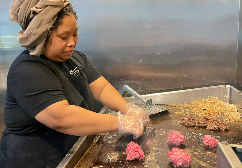 Owner Mariane Rony is shown creating a smash burger.