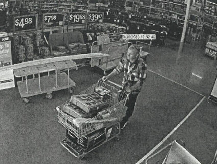A surveillance camera still of the suspect with a cart filled with store items.