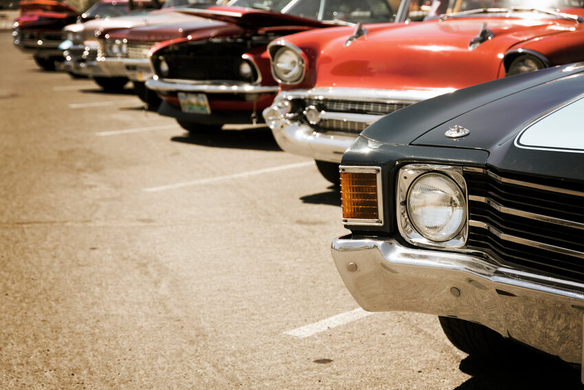 Classic cars are parked in a row on the street.