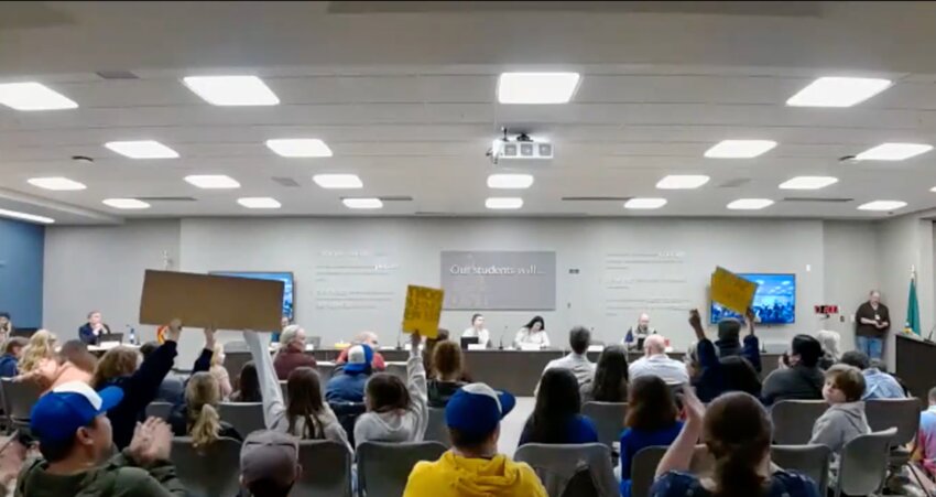 Young students from Olympia schools showed up to the board meeting to protest school closures, and they waved banners to support their classmates commenting on the podium.