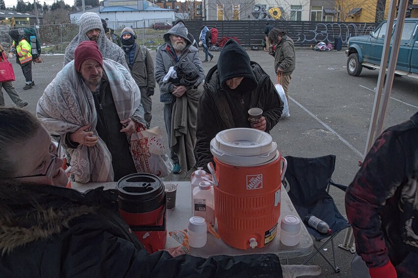 Mama Dee (lower left) gives directions while members of the homeless community line up for coffee, water or Tang.