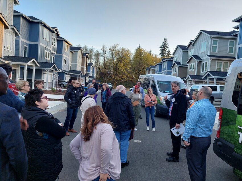 Tumwater City Council and Planning Commission members, along with citizens, listen to City Planning Manager Brad Medrud (right center of photo, in black jacket) pointing out features of a new development, Forest Park Townhomes, in a tour of existing middle housing. The tour serves to provide ideas as the city updates its Comprehensive Plan.