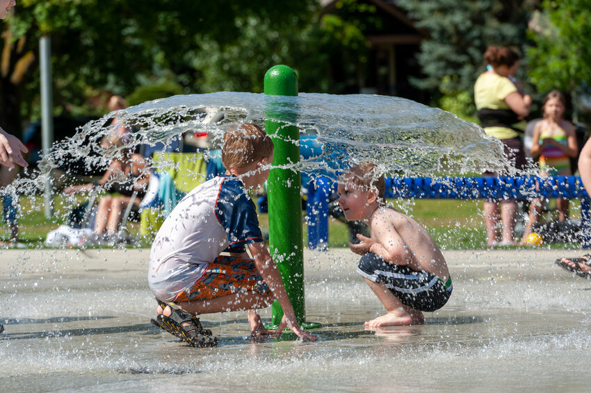 Two youngsters sit inside the spray at the splash pad at Woodruff Park.