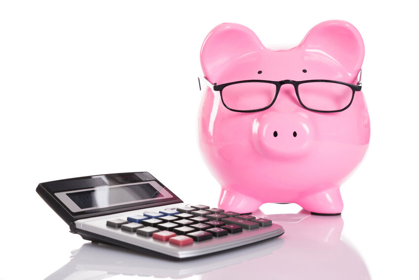 Piggy bank with glasses over a calculator.