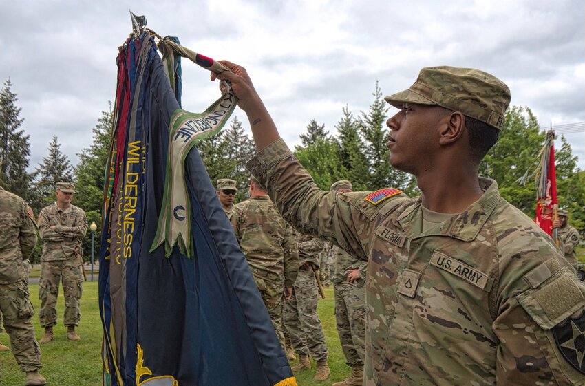 A soldier assigned to 1st Battalion, 23rd Infantry Regiment adjusts the campaign streamers on the regimental flag prior to a Memorial Day Remembrance at Joint Base Lewis-McChord.