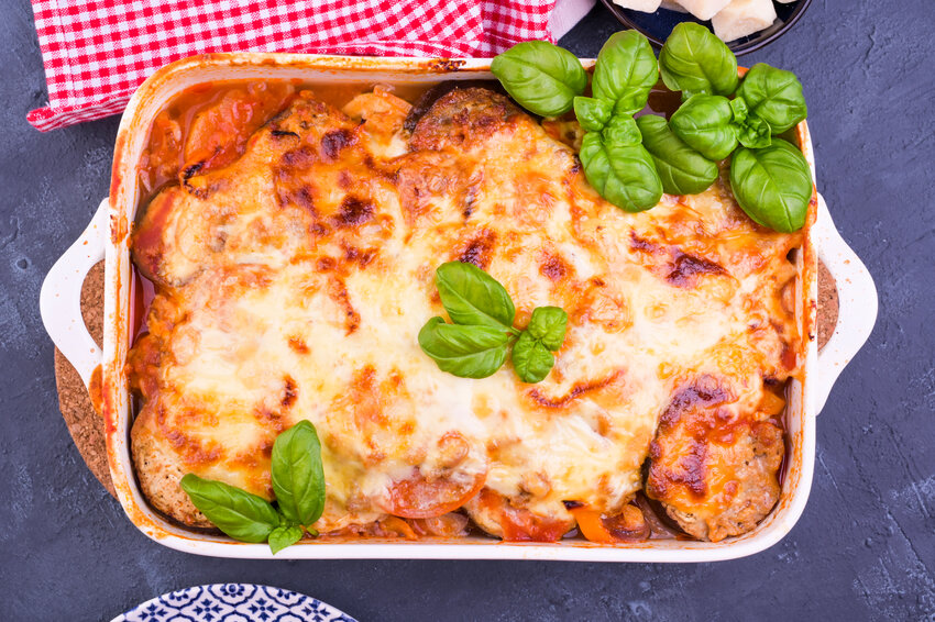 Healthy zucchini lasagna bolognese in a baking dish with olive oil. Oven-baked traditional Italian cuisine with mozzarella, parmesan, basil and vegetables.