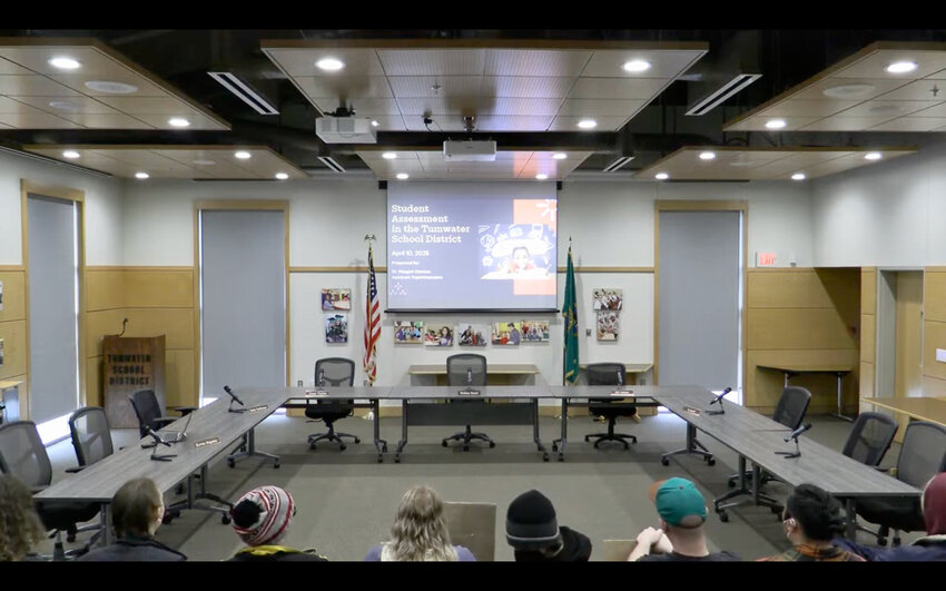 Some protesters can be seen holding signs inside the audience area of the Tumwater School District Board of Directors meeting. A district representative later said the protesters brought large metal cans with coins under their chairs.