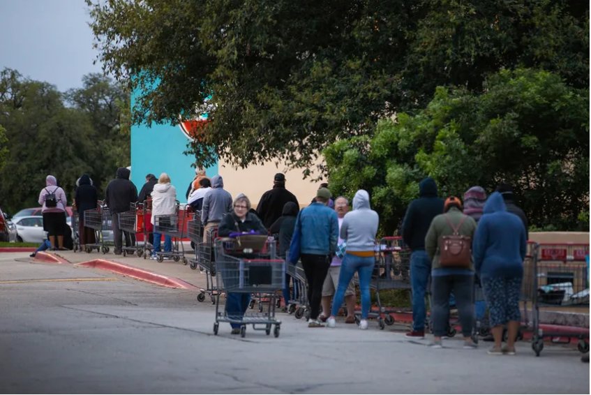 Shoppers line up with carts outside an H-E-B prior to opening. The COVID-19 outbreak has caused H-E-B to shorten its store hours in order to restock its inventory and better serve customers. March 21, 2020.