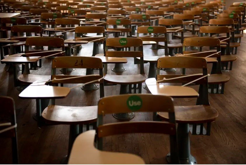 Desks are zip-tied and a green &quot;Use&quot; sticker is placed on available desks to practice social distancing in an academic hall at the University of Texas at Austin on Aug. 24, 2020.