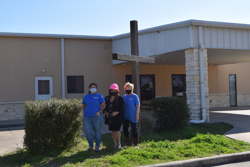 Katy Christian Ministries Executive Director Deysi Crespo (center in pink hardhat) poses with KCM Business Development Manager Jeannette Trejo (left) and KCM Master Gardener Karen Smith (right) in front of KCM&rsquo;s new headquarters building at 3506 Porter Road in the Katy area. The new facility will allow the nonprofit to consolidate operations, enlarge its food pantry and enhance its community garden.