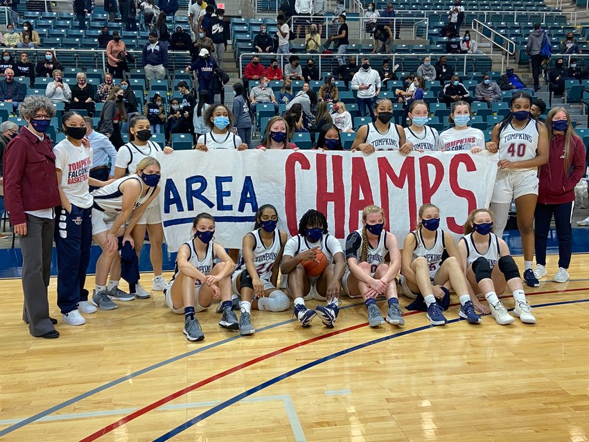 Tompkins' girls basketball coaches and players celebrate with an area playoff championship banner following their win over Memorial on Saturday at the Merrell Center.