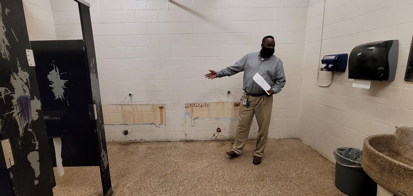 RISD Operations Director Derrick Dabney shows where urinals are missing from the walls in the boys&rsquo; bathroom and Royal Junior High School. Collapsed drainpipes in the walls and under the floor have prevented the installation of new urinals &ndash; one of many serious maintenance issues at the half-century-old campus.