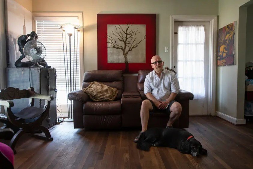 Tomas Garcia sits in his home with his dog, Patches, in Houston on Wednesday. Teachers report being spread thin by the demands of remote learning and exhausted by the constant health concerns.