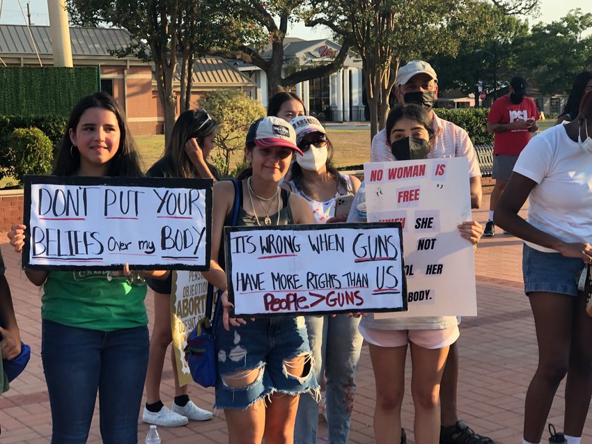 From left, Maria Luna, Francesca Mazzetto, and Neha Rao hold posters at the July 13 Katy Fights Back rally. Rao&rsquo;s partially obstructed sign on the right reads, &ldquo;No woman is free when she cannot control her own body.&rdquo;