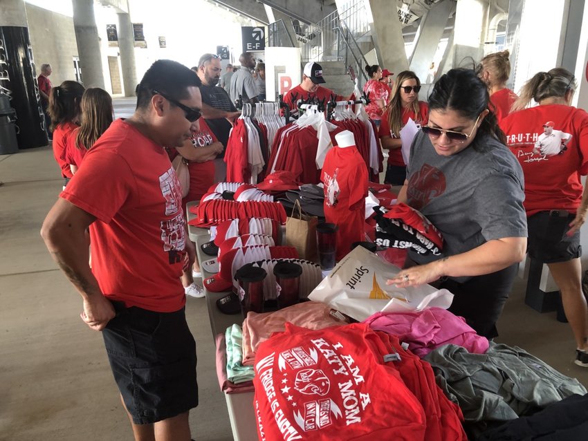 The Katy Athletic Booster Club unveiled a new line of Tiger swag at Monday&rsquo;s pep rally, including a t-shirt that pays tribute to coach Gary Joseph. The shirt proclaims, &ldquo;In Joseph We Trust.&rdquo; Here, Tigers fan Arturo Medina purchases some swag from Booster Club volunteer Nichole Price.
