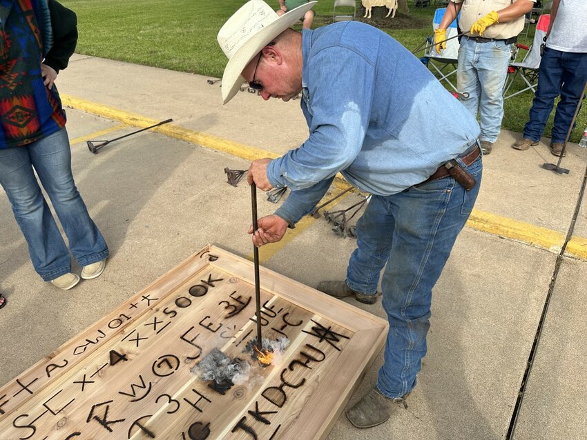 Kurt Klausmeyer applies a brand to a display that will one day hang in a new Waller County Courthouse in Hempstead. He said if one sees blue smoke when applying the brand, one is done and can proceed to the next branding.