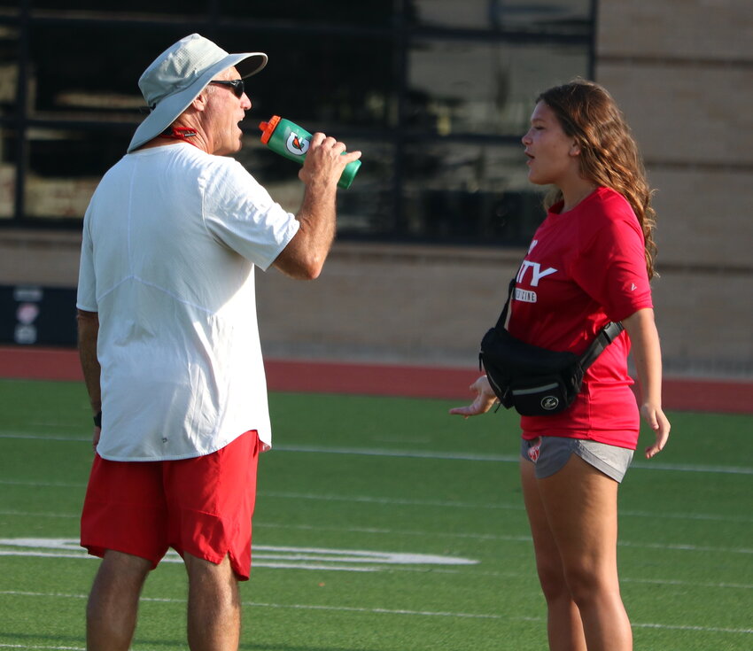 Ellie Capiro gives Katy head football coach Gary Joseph a water bottle during a practice.